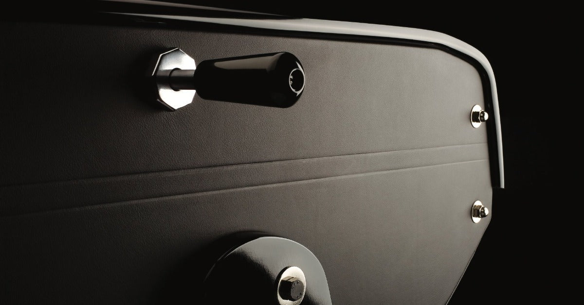 A detailed view of a black foosball table shows textured surfaces, polished hardware, and precision craftsmanship.